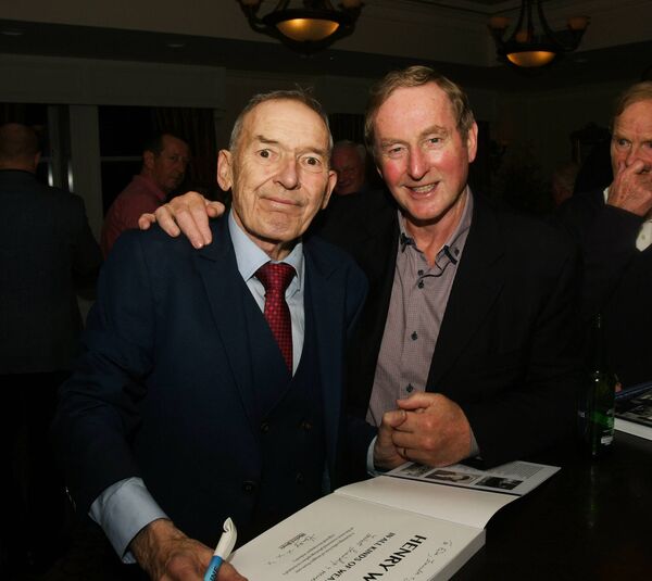 Henry Wills signs a copy of his new book for former Taoiseach Enda Kenny. Picture: John O'Grady