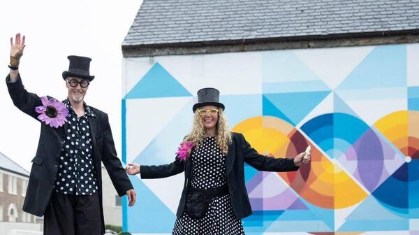 Stilt walkers in front of the mural commissioned for Belmullet 200.