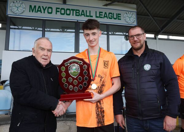 Pat Quigley presents the Eleanor Quigley Shield to Jack Flatley, captain of Straide and Foxford Utd, after they defeated Ballyhaunis Town in the final in Solar 21 Park, Castlebar, earlier this year. Included on right is Seamus Hughes, chairman, Mayo League. Picture: Michael Donnelly Pat Quigley presents the Eleanor Quigley Shield to Jack Flatley, captain of Straide and Foxford Utd, after they defeated Ballyhaunis Town in the final in Solar 21 Park, Castlebar, earlier this year. Included on right is Seamus Hughes, chairman, Mayo League. Picture: Michael Donnelly