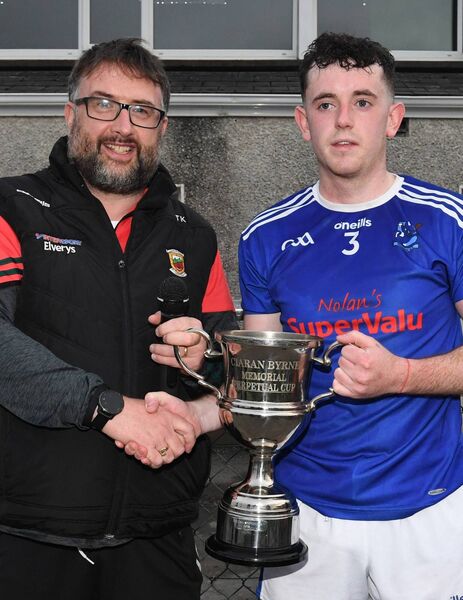 County Hurling GAA Board Secretary, Trevor Kelly, presents Tooreen captain, Jack Trench, with the Ciaran Byrne Memorial Cup. 
