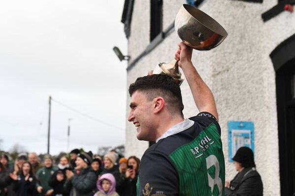 Ballina captain Luke Sweeney lifts the Cawley Cup in front of jubilant teammates and supporters.