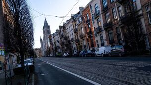 <p>A tram street lined with parked cars and row houses leading to a church tower in Etterbeek, Brussels. 	Picture: Martin Bertrand/Hans Lucas/AFP via Getty Images</p>