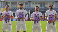 Iran wear black armbands and hold schoolbags during national anthem before match