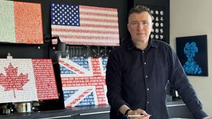 <p>Artist Gary McGinty with his 'Spoken State' works, showcasing messages of peace.</p>