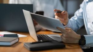 <p>Businessman reviewing documents and working on a laptop during an office meeting, showcasing professionalism and fostering collaboration among team members in a corporate environment</p>
