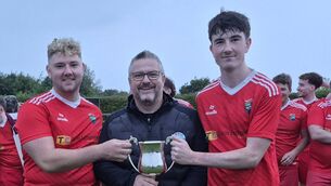 <p>Ballinrobe Town duo Iarla Killeen, leftm and Conor Keleghan, right, receive the McDonnell Construction League Two trophy from Colin Redmond of the Mayo Football League. Picture courtesy of the Mayo Football League</p>