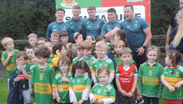 The children in Kilmovee enjoying the moment with the Sam Maguire Cup and members of the Mayo team when they visitied Kilmovee Shamrocks GAA Club last week.